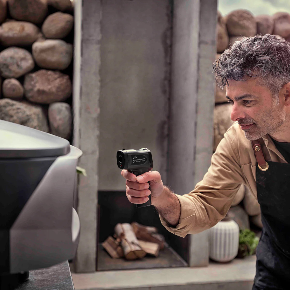 Man using a black Witt Infrared Temperature Gun in front of a Witt Oven pizza
