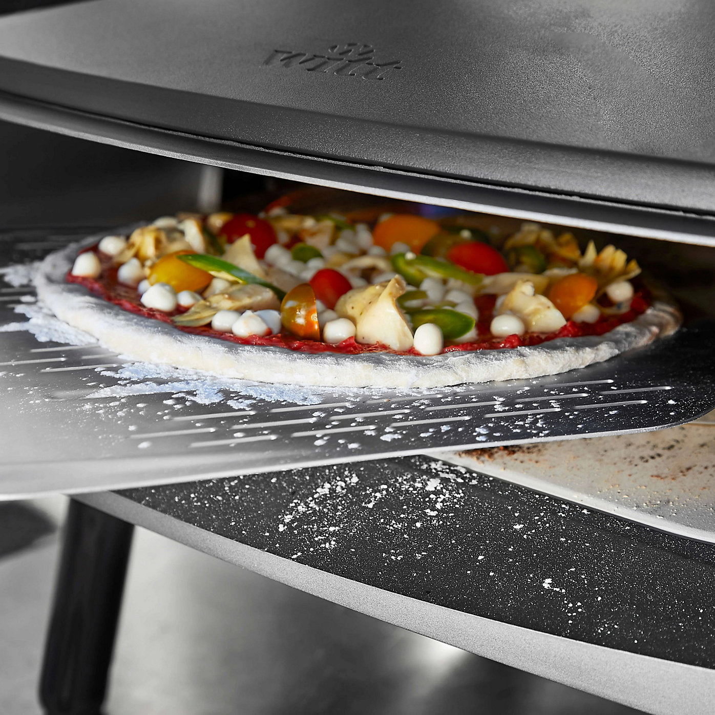 Pizza with various toppings being cooked in a Wiltt pizza oven.